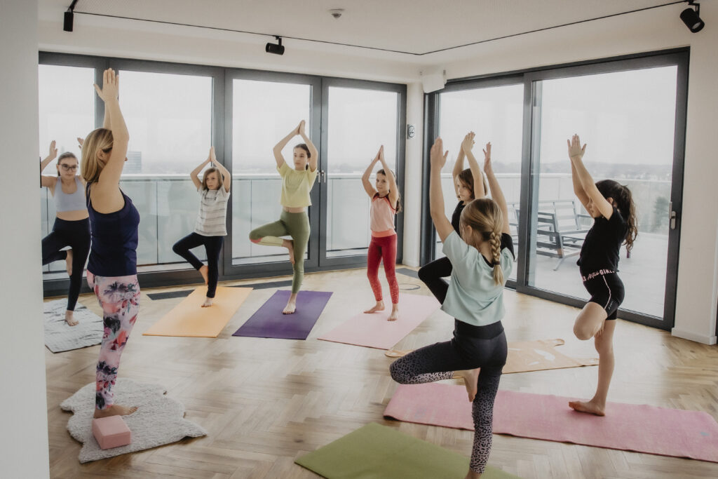 Kinderyoga: Kinder mit Trainerin bei einer Yogaübung